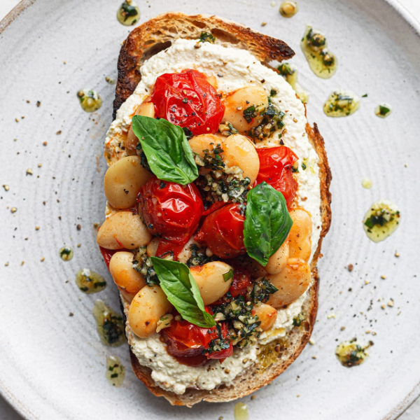 Vegan Fndly recipe image showing butter beans, tomatoes, and tofu “ricotta” on toasted bread for a plant-based dish.
