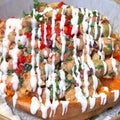 Stuffed sweet potato with chickpeas and tahini sauce, a healthy vegan recipe from Vegan Fndly, topped with fresh herbs and ingredients.