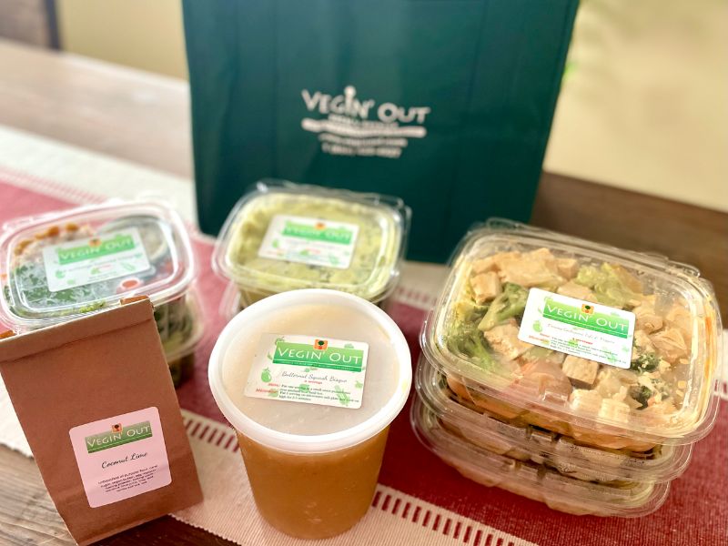 Vegin' Out vegan meal delivery set featuring fresh vegetarian and vegan dishes arranged on a wooden table.