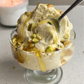Vegan Fndly pistachio ice cream recipe image with creamy pistachio mixture in a bowl and fresh pistachios on the side.